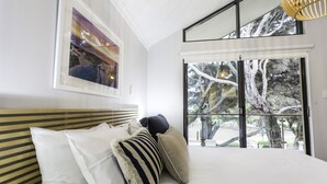 Un dormitorio con una cama grande, una ventana con vistas a árboles y un cuadro en la pared.