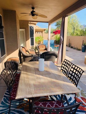 Une terrasse extérieure avec une table, des chaises et un ventilateur de plafond.