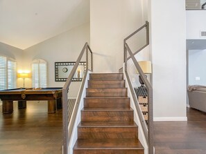 Una escalera con escalones de madera y barandales de metal, que conduce a un segundo piso.