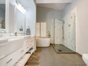 Une salle de bain moderne avec un meuble-lavabo blanc, un grand miroir, une baignoire et une douche séparée par une paroi en verre.