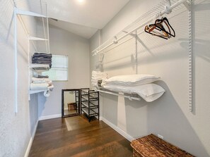 A laundry room with shelves for folded towels, a drying rack, and a wicker basket.