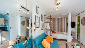 Een moderne woonkamer met een blauwe bank, een houten salontafel en een hanglamp.