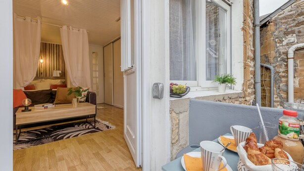 Een gezellige kamer met een bed, een klein tafeltje met ontbijtartikelen en uitzicht op een stenen gebouw.