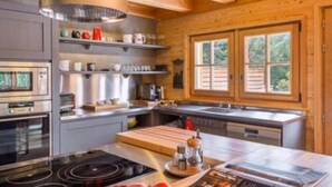 Una cocina moderna con vigas de madera, electrodomésticos de acero inoxidable y un ventanal grande.