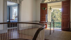 A grand hallway with a wooden railing, a large open door leading outside, and a decorative mirror on the left. - Historic Rockwell House (Milledgeville)