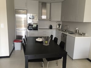 Una cocina moderna con comedor, electrodomésticos de acero inoxidable y una distribución compacta.