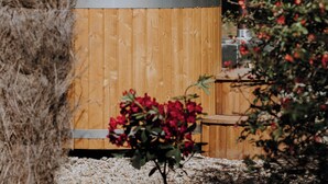 A wooden structure with a metal band, surrounded by gravel and plants. - La Cabane Magique Des Fichettes (Sandillon)