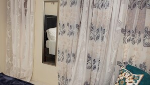 A bedroom with a bed, a chair with a pillow, and a mirror on the wall.