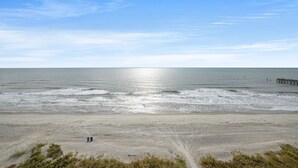 A beach with a sandy shore, a small structure, and a pier extending into the water.