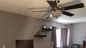 A bedroom with a bed, a ceiling fan, a TV, a chair, and a shelf with pictures. - Private condo sleeps up to 4 with private hot tub (Lincoln)