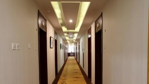 A long, narrow hotel corridor with wooden doors, framed pictures on the walls, and a patterned carpet. - Greentree Alliance Hulunbeier Zhalantun Railway Station Hotel (Hulunbuir)