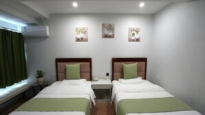 A hotel room with two beds, each with a green pillow and white bedding. There are wall-mounted air conditioning units and three wall art pieces above the beds. - Greentree Alliance Hulunbeier Zhalantun Railway Station Hotel (Hulunbuir)