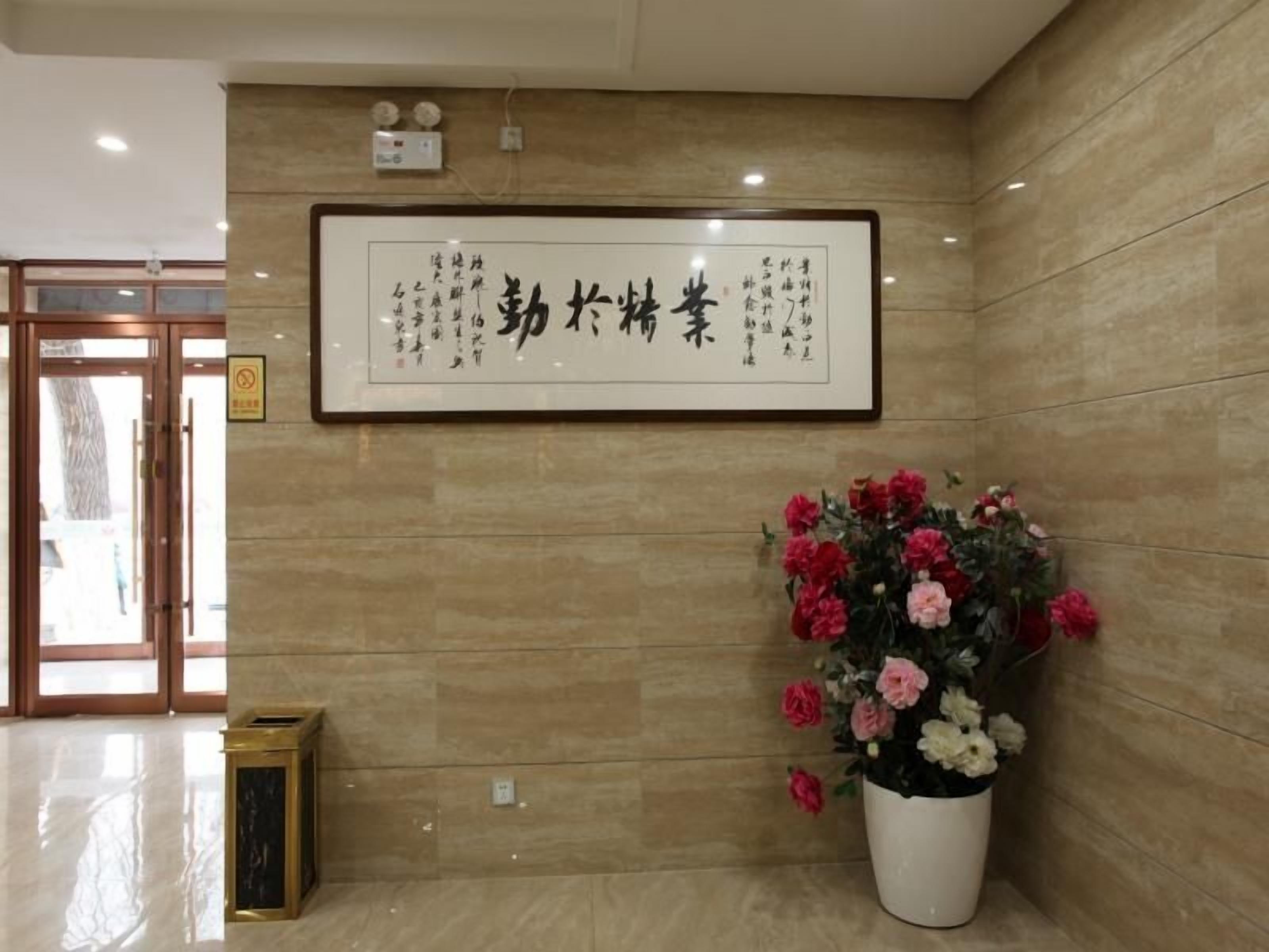 A reception area with a framed sign, a potted plant, and a trash bin.
