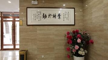 A reception area with a framed sign, a potted plant, and a trash bin.