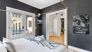 Un dormitorio con una cama grande, un televisor y un mapa de Charleston en la pared.
