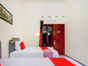 A hotel room with two beds, a wooden door, and a painting on the wall. - OYO 90151 Guest House 180 (Batu)