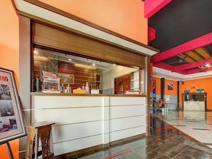A reception area with a counter, a framed picture, and a sign indicating a check-out time. - OYO 90151 Guest House 180 (Batu)
