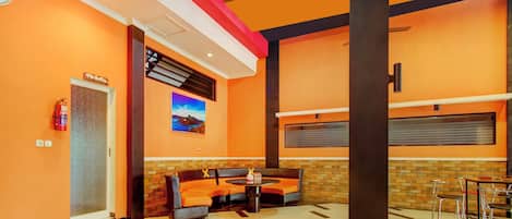 Un hall con mostrador de recepción, zona de estar y extintor.