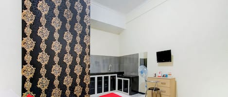 A hotel room with a bed, a desk, a chair, a TV, and a wardrobe.