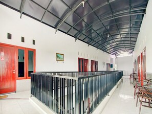 A corridor with a metal railing, red doors, and a tiled floor. - OYO 90151 Guest House 180 (Batu)