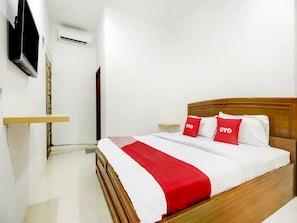 A neatly arranged hotel room with a wooden bed, white bedding, and red accents. - OYO 3929 8angau Mas (Palembang)