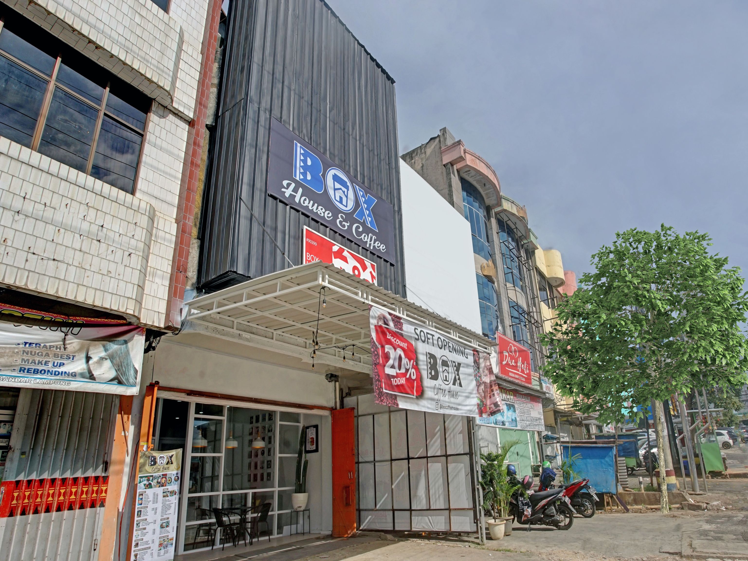 Un edificio comercial con varias tiendas, incluyendo una cafetería y una tienda con un cartel de 20% de descuento.