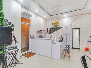 A reception area with a white desk, a reception sign, a door, and a window. - Box House (Bandar Lampung)