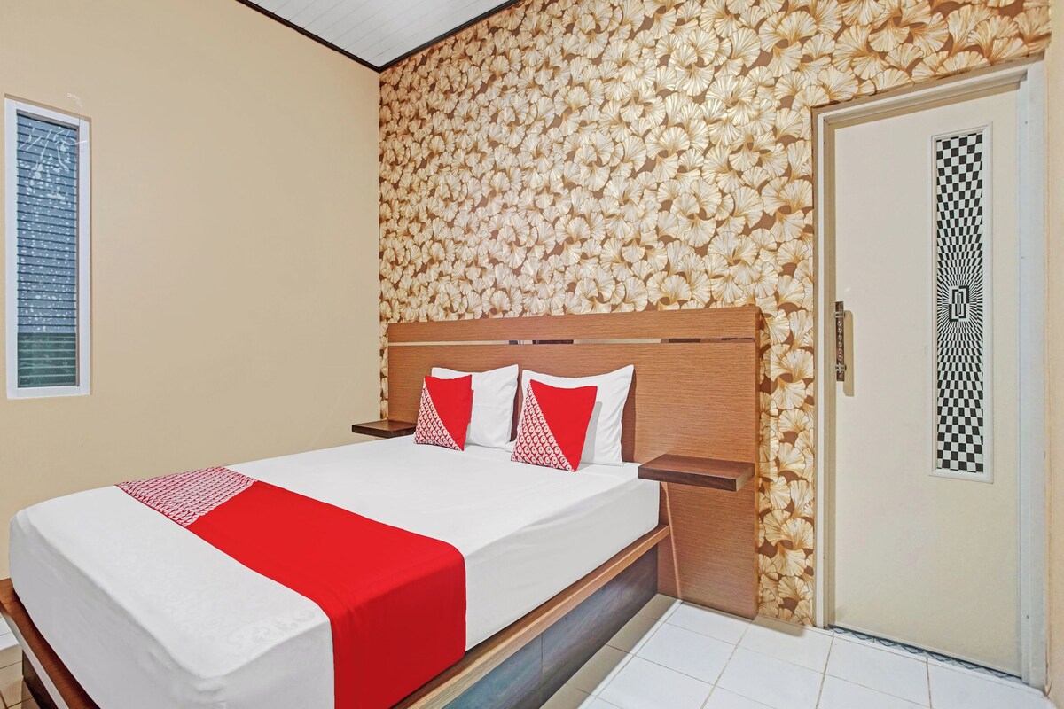A hotel room with a bed, wooden headboard, and a patterned wall.