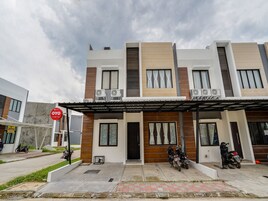 Un edificio moderno de dos pisos con techo plano, varias unidades de aire acondicionado y un área de entrada cubierta.