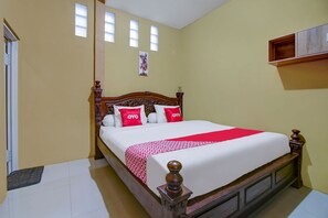 A hotel room with a wooden bed, a red and white bedspread, and a single window with blinds. - OYO 90061 Melati House Syariah (Kepanjen)