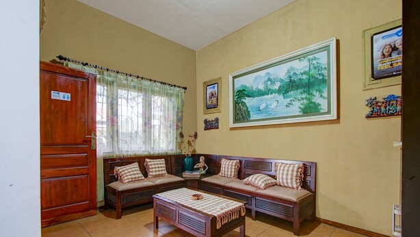 Un salon avec un ensemble de meubles en bois, dont un canapé, une table basse et un grand tableau représentant un paysage accroché au mur.