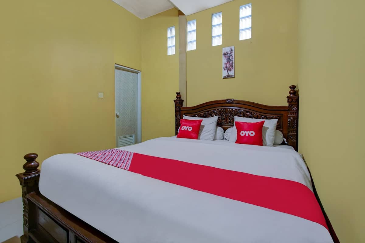 Quarto com cama de madeira, paredes amarelas e janela com vista.