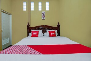 A bed with a white and red bedspread, two pillows with 'OYO' branding, and a wooden headboard. - OYO 90061 Melati House Syariah (Kepanjen)