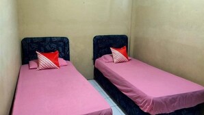 Two single beds with pink bedding and patterned pillows in a small room with plain walls. - Hotel Sinar Lumayan Syariah (Balikpapan)