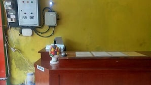 A reception desk with a PLN GENSET sign, a fruit vase, and a water dispenser. - Hotel Sinar Lumayan Syariah (Balikpapan)
