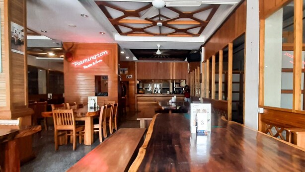 L’intérieur d’un restaurant est aménagé avec des meubles en bois, un long comptoir et un plafond orné de motifs géométriques.