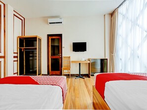 A hotel room with two beds, a desk, a chair, a TV, and a wardrobe.