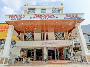 Une auberge de jeunesse avec une enseigne indiquant « Remington Resto & Café », un service de massage et de réflexologie, et un four à pizza de type « Pintu ».