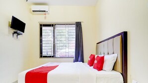 A hotel room with a bed, a TV mounted on the wall, a window with curtains, and an air conditioning unit. - OYO 90052 Star House (West Cirebon)