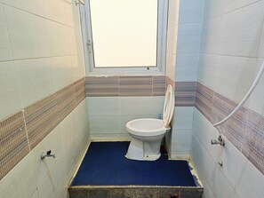 Une petite salle de bain avec des toilettes, une fenêtre et des murs carrelés.