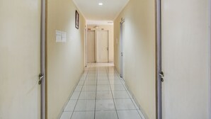 A corridor with doors labeled B10 and B9, white tiled flooring, and a ceiling light. - OYO 4008 E Paviliun Karawaci (Curug)