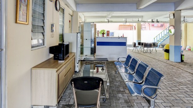 Zona de recepción con mostrador, computadora, teléfono y área de asientos con sillas.