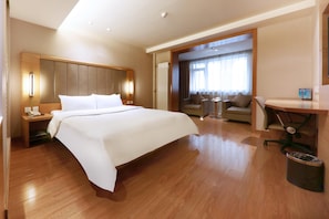 Quarto de hotel com uma cama grande, uma mesa, uma cadeira e um sofá.