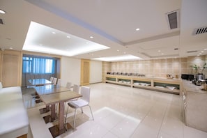 Quarto de hotel moderno com área de jantar, cozinha e uma grande janela com cortinas.
