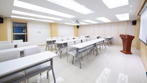 A conference room with white tables and chairs, a podium, and a projector screen. - Ji Hotel Urumqi Youhao (Ürümqi)