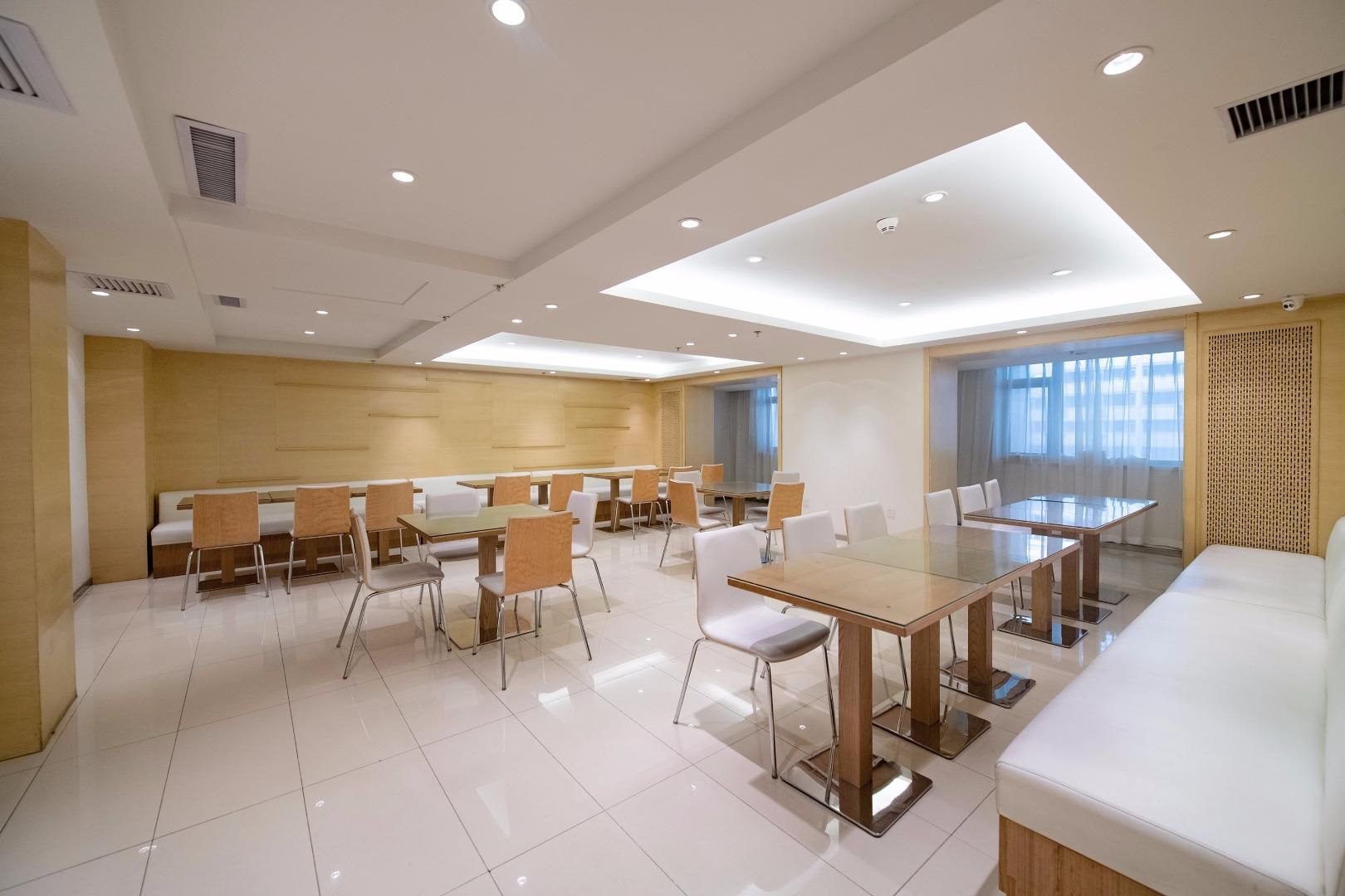 A modern conference room with a glass table, white chairs, and a white sofa.