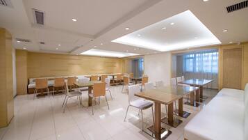A modern conference room with a glass table, white chairs, and a white sofa.