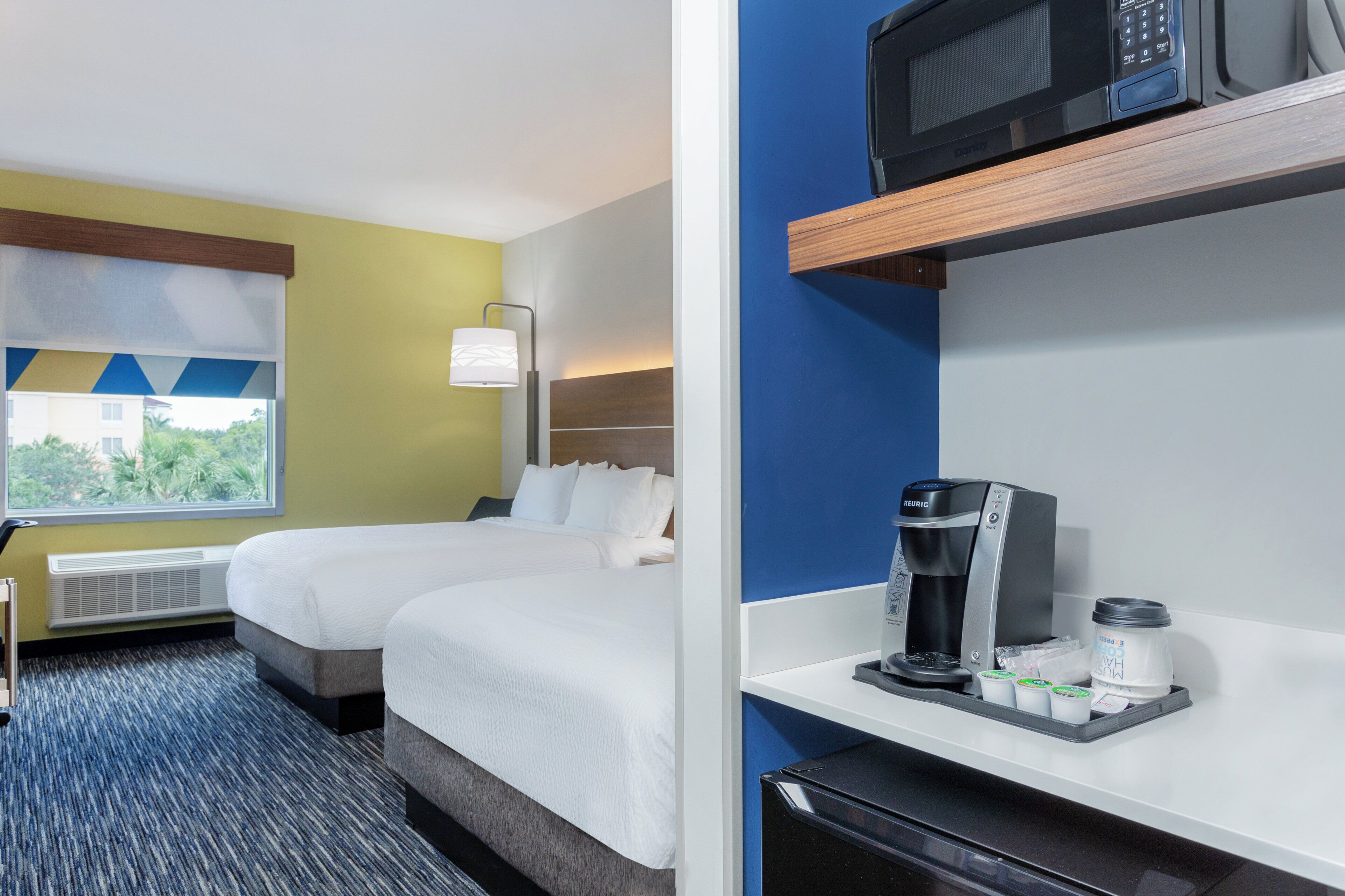 Quarto de hotel com duas camas, janela com vista, minibar e micro-ondas.