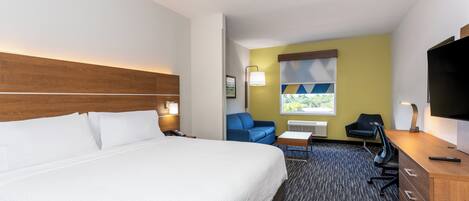 A hotel room with a bed, a desk, a chair, a sofa, and a television.