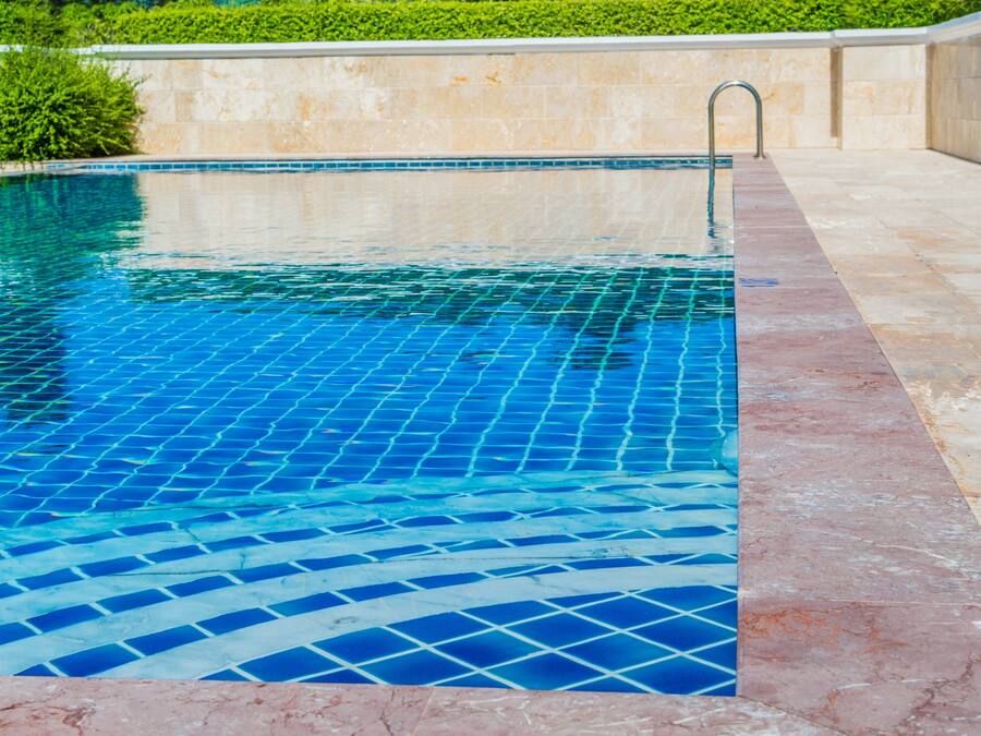 A swimming pool with a tiled edge and a metal ladder.